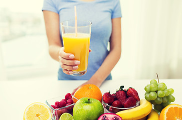 Image showing close up of woman holding orange juice with fruits