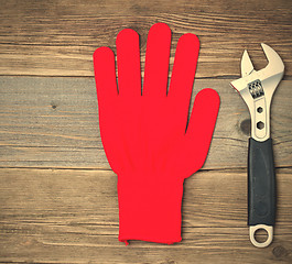 Image showing Red protective glove and an adjustable pipe wrench