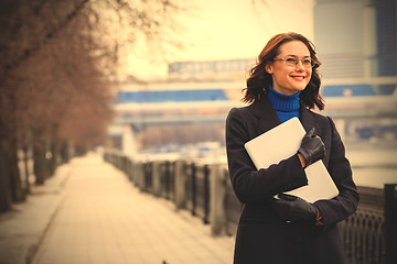 Image showing smiling woman with a laptop outdoors