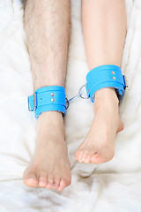 Image showing male and female legs in handcuffs. couple in bed. sex Toys