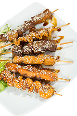 Image showing Grilled juicy skewered shashlik on a plate, sesame