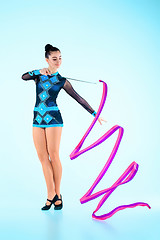 Image showing The girl doing gymnastics dance with colored ribbon on a blue background