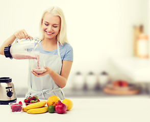 Image showing smiling woman with blender and fruit milk shake