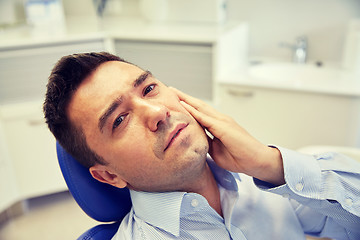 Image showing man having toothache and sitting on dental chair