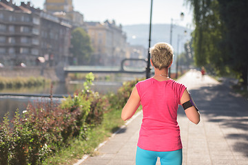 Image showing jogging woman setting phone before jogging