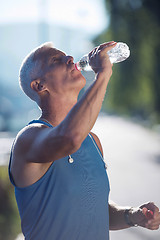 Image showing senior jogging man drinking fresh water from bottle