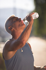 Image showing senior jogging man drinking fresh water from bottle