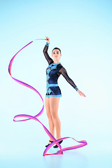 Image showing The girl doing gymnastics dance with colored ribbon on a blue background