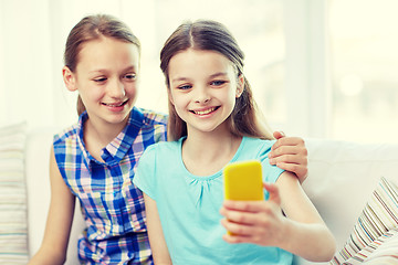 Image showing happy girls with smartphone taking selfie at home