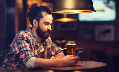 Image showing man with smartphone and beer texting at bar