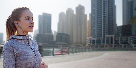 Image showing happy woman with earphones running over dubai city