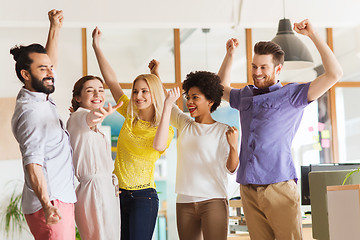 Image showing happy creative team celebrating victory in office