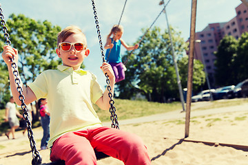 Image showing two happy kids swinging on swing at playground