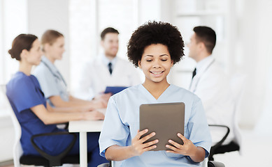 Image showing happy doctor with tablet pc over team at clinic