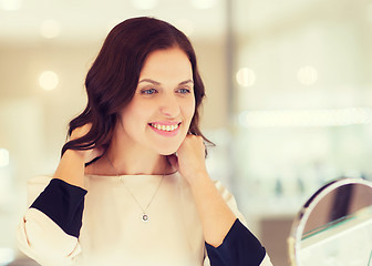 Image showing happy woman choosing pendant at jewelry store