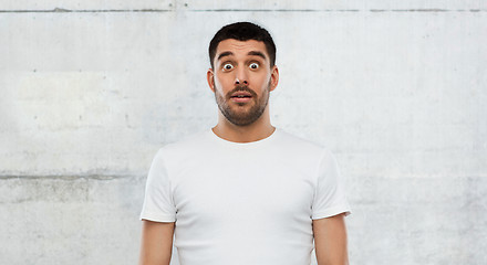 Image showing scared man in white t-shirt over wall background