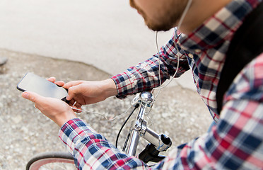 Image showing hipster man in earphones with smartphone and bike