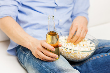 Image showing close up of man with popcorn and beer at home