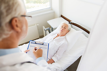 Image showing senior woman and doctor with clipboard at hospital