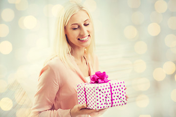 Image showing smiling woman with gift box over holidays lights