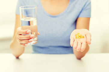 Image showing close up of woman hands with capsules and water