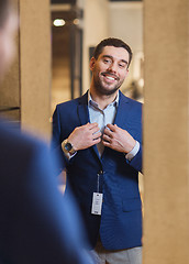 Image showing man trying jacket on at mirror in clothing store