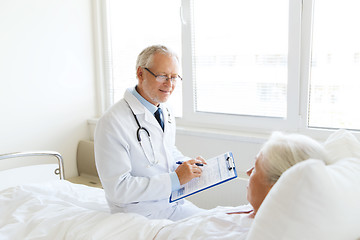 Image showing senior woman and doctor with clipboard at hospital