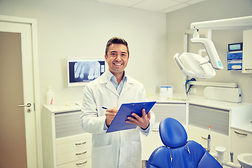 Image showing happy male dentist with clipboard at dental clinic