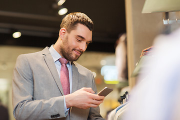 Image showing man in suit with smartphone at clothing store