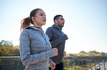 Image showing happy couple with earphones running outdoors