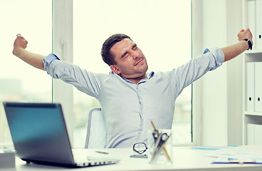 Image showing bored businessman with laptop and papers at office