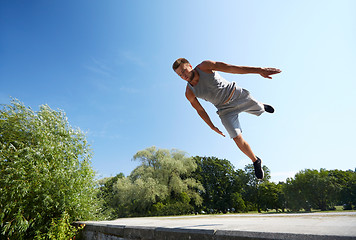 Image showing sporty young man jumping in summer park