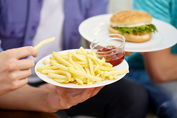 Image showing close up of male hands with fast food on plates