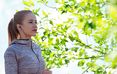 Image showing happy woman with earphones running in city
