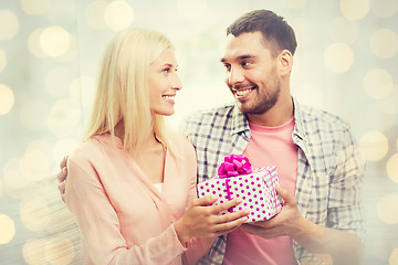 Image showing happy man giving woman gift box over lights