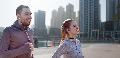 Image showing happy couple with earphones running in city