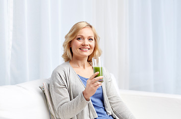 Image showing happy woman drinking green juice or shake at home