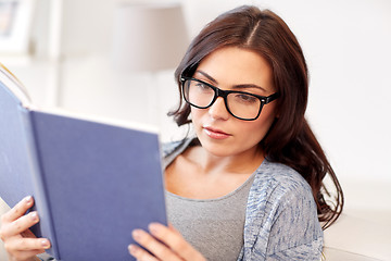 Image showing young woman in glasses reading book at home