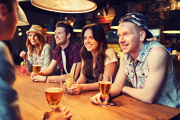 Image showing happy friends with drinks talking at bar or pub