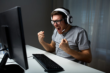 Image showing man in headset playing computer video game at home