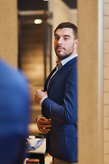 Image showing man trying jacket on at mirror in clothing store