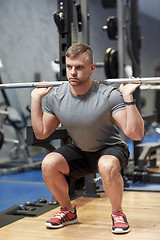 Image showing young man flexing muscles with barbell in gym