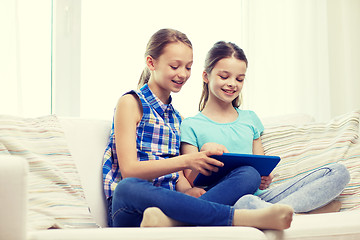 Image showing happy girls with tablet pc sitting on sofa at home