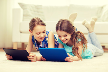 Image showing happy girls with tablet pc lying on floor at home