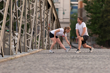 Image showing couple warming up and stretching before jogging