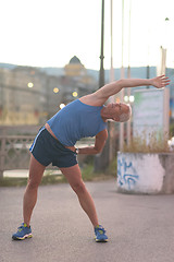 Image showing handsome man stretching before jogging