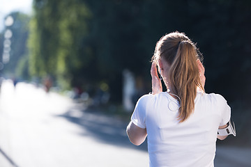 Image showing jogging woman setting phone before jogging