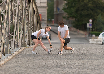 Image showing couple warming up and stretching before jogging