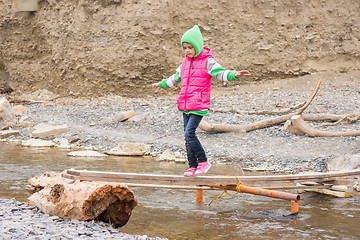 Image showing Girl seven years is on rickety bridge over the creek arms outstretched for balance