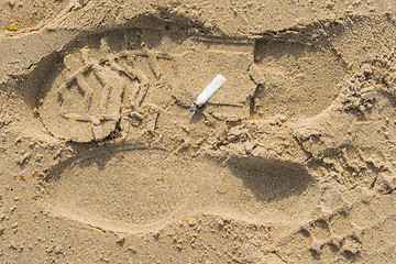 Image showing stub of a cigarette lying on the sand on a sea beach